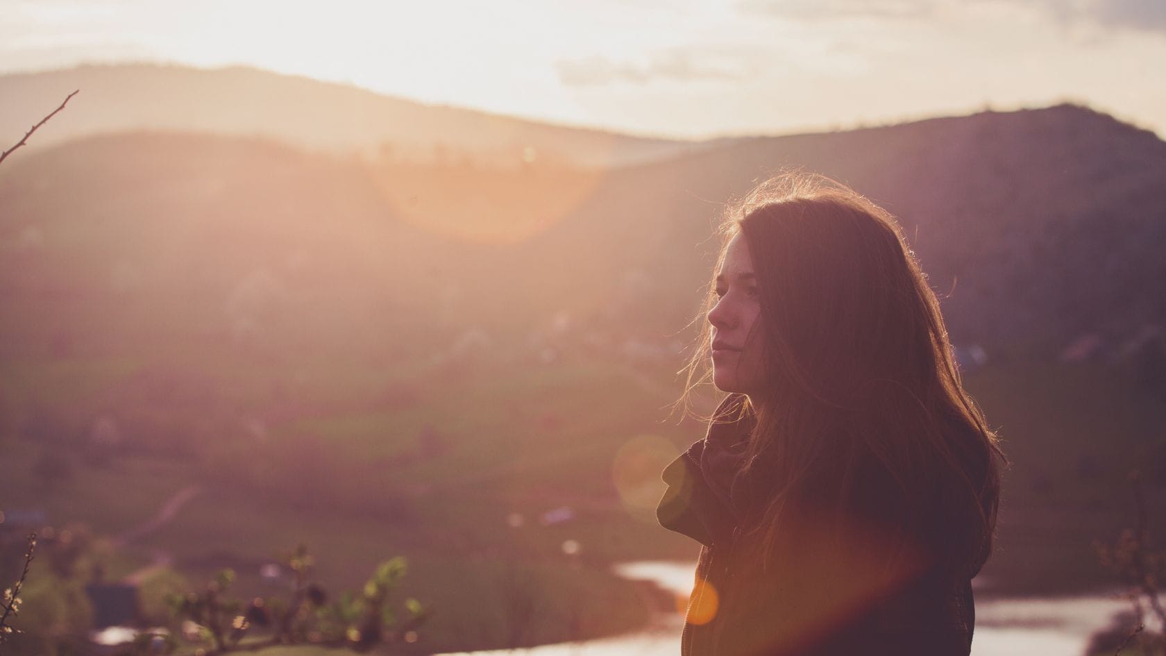 woman looking into the distance in nature surrounded by postpartum herbs