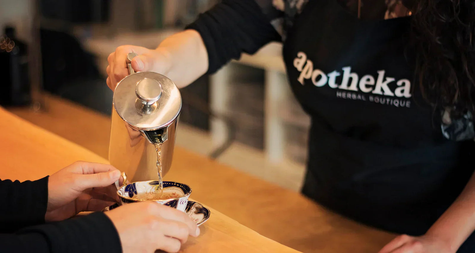 herbalist wearing apotheka sweater pouring out tea Apotheka Herbal